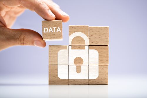 A person sets a wood cube onto other stacked wood cubes, and together, they complete the image of a lock icon with the word "data."
