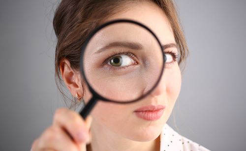 Inquisitive woman looking through magnifying glass.