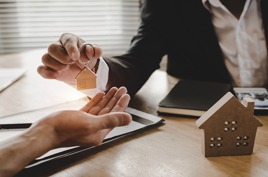 Portland, OR Real Estate Broker giving house key to customer after signing contract.