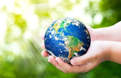 Planet in child hands on against green spring background