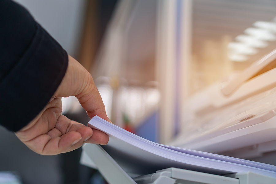 Portland OR office worker feeding documents into a scanner