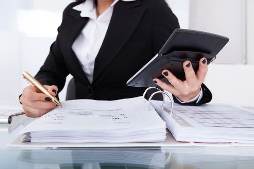 An accountant is calculating tax at desk in office
